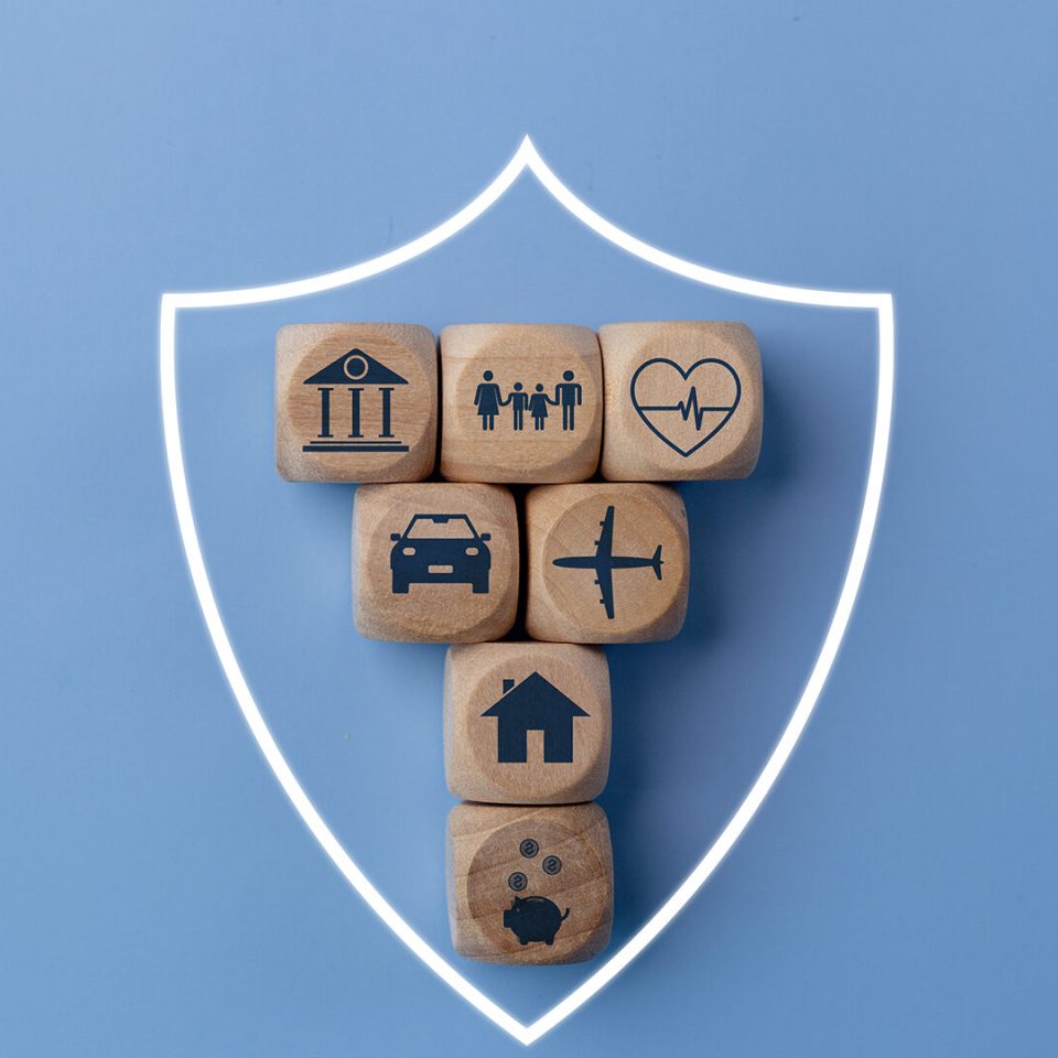 Life Insurance concept with wooden blocks and icons of various types of insurance on a blue background.